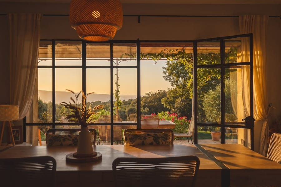 La table, la baie vitrée et le Luberon au couchant